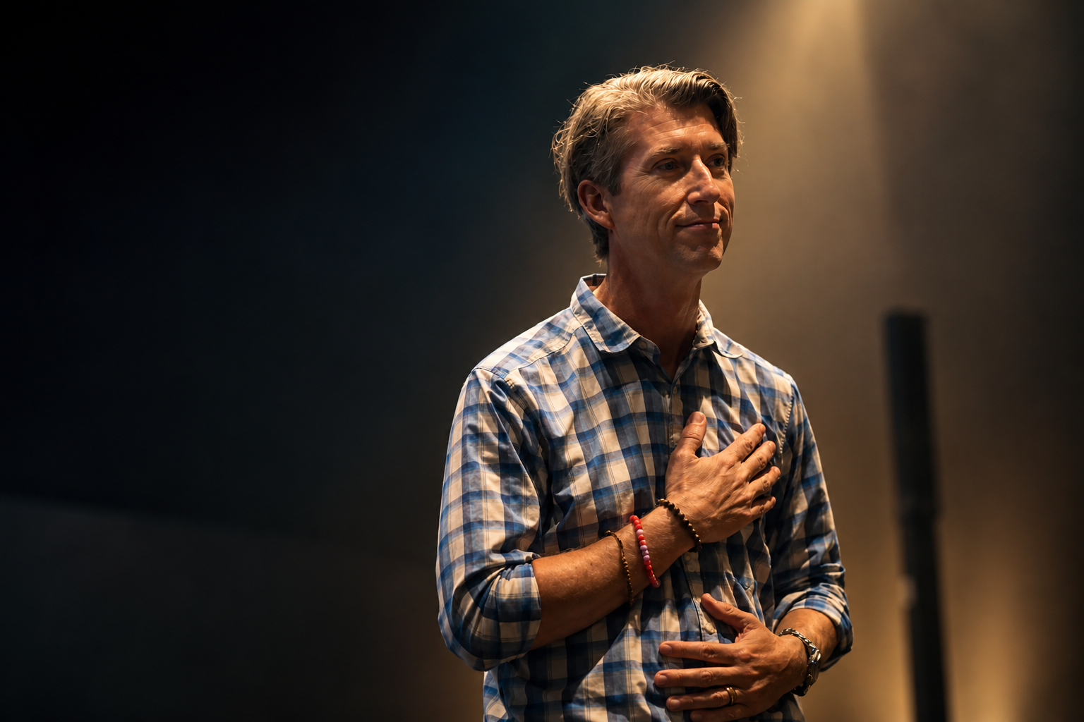 Ron Perry on stage under a single warm light
